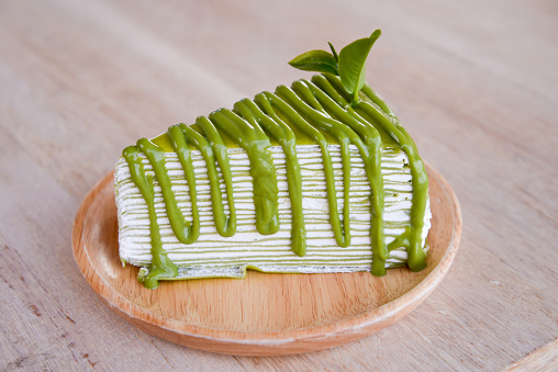 Crepe cake flavored green tea on a wooden plate.
