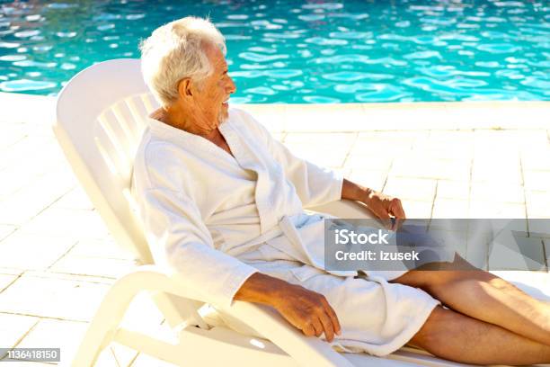 Senior Man Relaxing On Deck Chair At Poolside Stock Photo - Download Image Now - Bathrobe, Swimming Pool, 70-79 Years