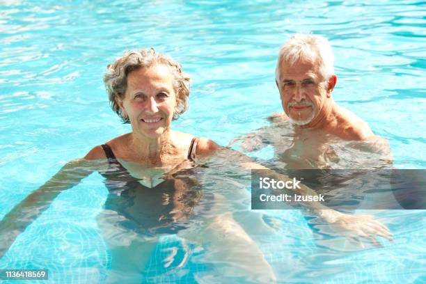 Portrait Of Happy Senior Couple Swimming In Pool Stock Photo - Download Image Now - Senior Adult, Swimming Pool, Swimming