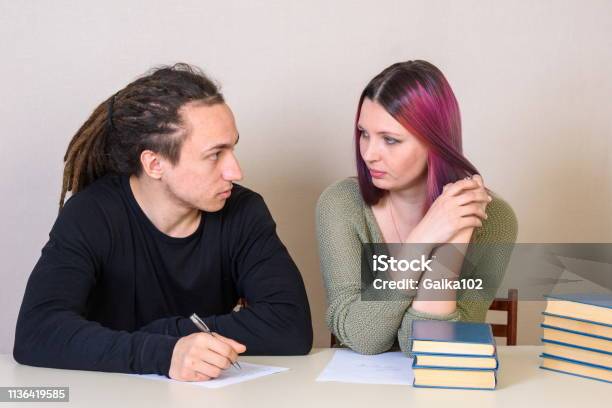 Young Girl And Teenager Look At Each Other At The Table Stock Photo - Download Image Now