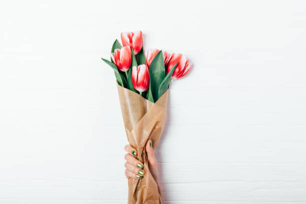 istock Woman's hand with green manicure holding bouquet 1136419626
