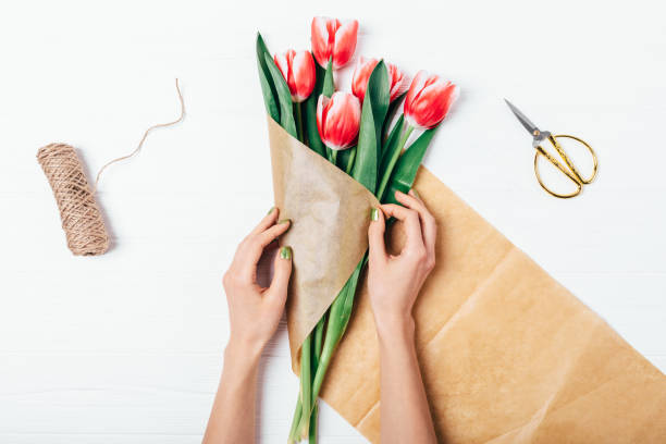 istock Woman's hands wrapping bunch of red tulips 1136419628