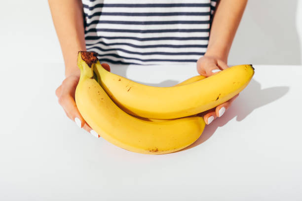 nahaufnahme der hände der frau mit weißer maniküre - banana bunch yellow healthy lifestyle stock-fotos und bilder