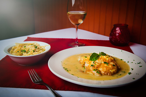Serving ofChicken Francese with a side of pasta and white wine