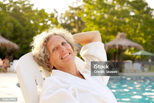Smiling Senior Woman Resting At Poolside Stock Photo - Download Image Now - One Woman Only, Only Women, 60-64 Years