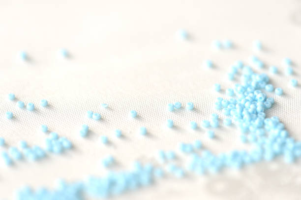istock Seed beads light blue color scattered on a textile background close up 1136421568