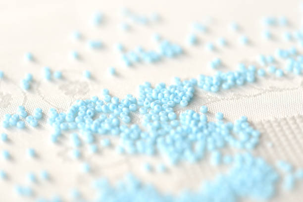 istock Seed beads light blue color scattered on a textile background close up 1136421571