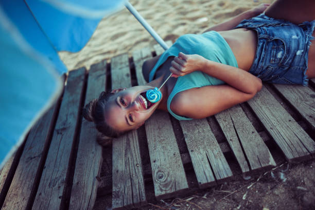 adorabile adolescente donna che si rilassa sotto l'ombrellone - umbrella beach sex symbol white foto e immagini stock