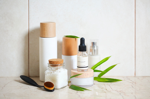 Crema facial, suero, loción, humectante y sal marina entre las hojas de bambú photo