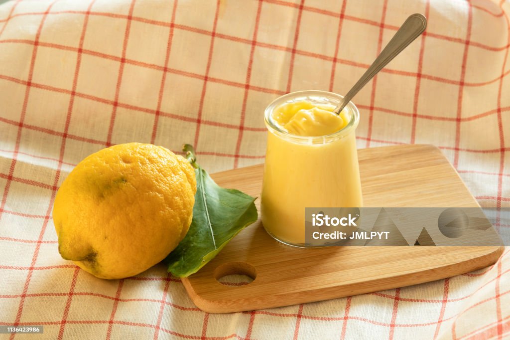 Yoghurt with lemon of Menton. Yoghurt with lemon of Menton. A single pot on a table and a white and red striped towel.
There is a spoon in the cream jar. Acid Stock Photo