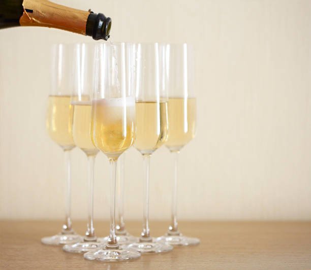 istock Pouring champagne from bottle into six transparent glasses 1136424452