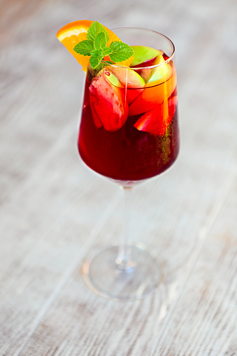 Glass of iced sangria with strawberry, orange, apple and lemon on the table. Close up
