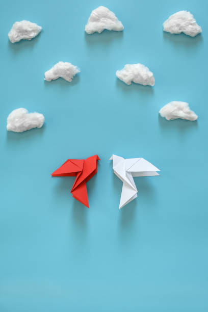 istock White and red paper pigeons on a blue background among white clouds. 1136428639