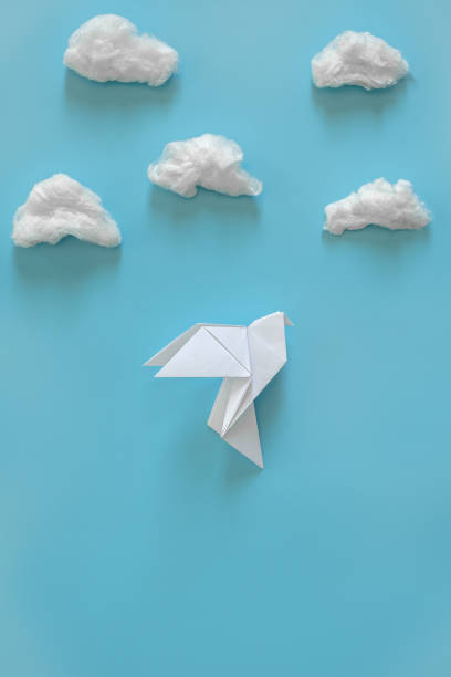 istock White paper dove on a blue background among the white clouds. Minimal concept 1136428679