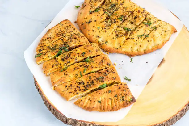 Stuffed Garlic Bread and Slices with Herbs. Popular Italian-American Food, Gray-White Background.