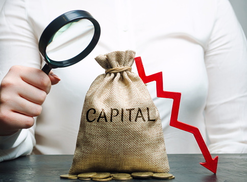 Woman analyzes data on the cost of capital in the company. Capital outflow. Unprofitable activity of the enterprise. Low capital ratio. Small income and deficit. Weighted average price indicator