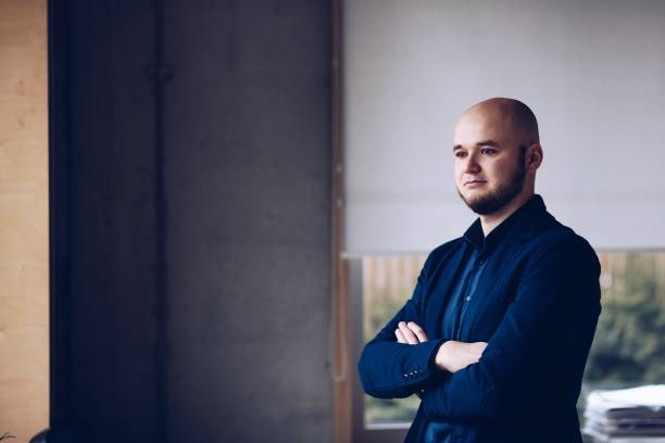 istock Young businessman standing by the window in the office. 1136429351