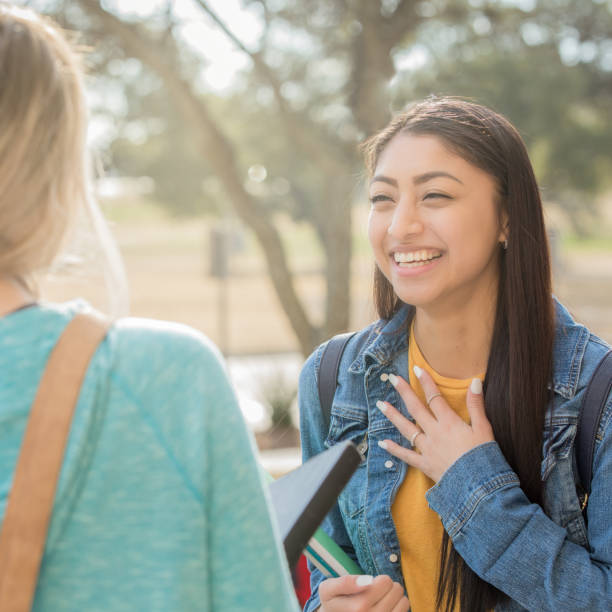 istock Beautiful Hispanic college student talks with friend about assignment outside on campus after class 1136432780