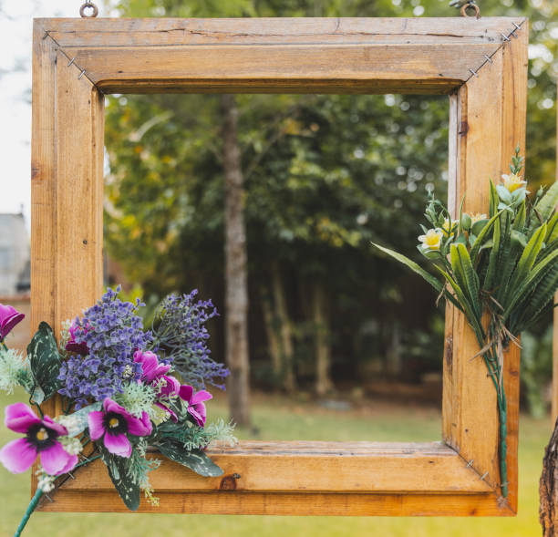 istock frame, decorated with flowers, hanging on a branch on green background. 1136433341