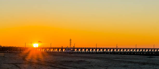 lange pier bij zonsondergang op het strand van blankenberge, belgië, zonsondergang met een kleurrijke hemel - blankenberge strand stockfoto's en -beelden
