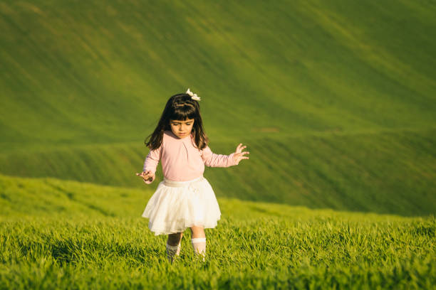 Little girl with pink shirt and skirt in a meadow. Disgusted face. she does not like the field