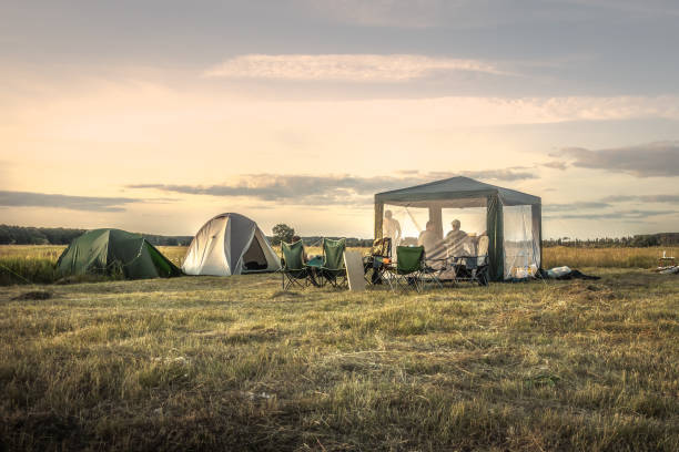 Camping site camping tents on summer field sunset sky during camping holidays