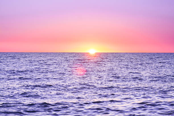 Sunset over sea below a yellow sun in a yellow sky at fall