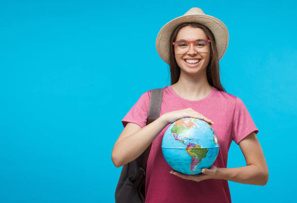 istock Smiling girl holding globe with both hands, isolated on blue background 1136438221
