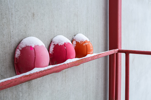 Old, worn, colorful and safety helmets of engineering construction workers with snow are on the hand railings of construction site