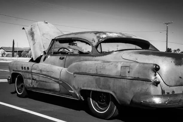 A broken down Buick with its hood up.