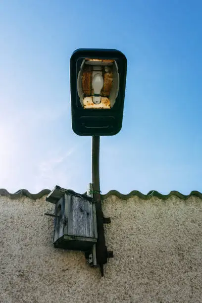 old lamp with house roof and bird box with view from below