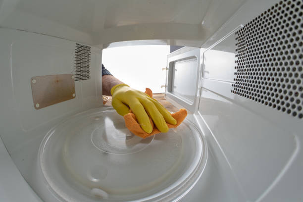 cleaning the inside of the microwave in the home kitchen. the device for heating dishes with the help of waves. light background. - domestic kitchen contemporary domestic room lifestyles imagens e fotografias de stock