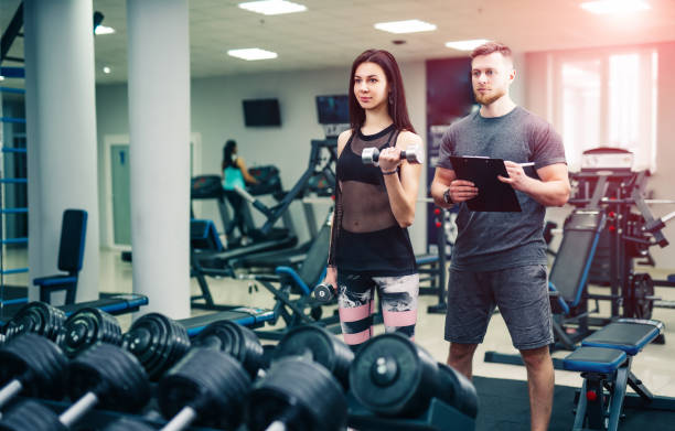 istock Personal trainer helping woman working with heavy dumbbells. 1136445496