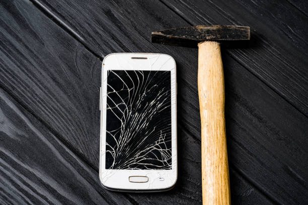 istock Touchscreen of a smartphone is broken with a hammer on the grey wooden background. 1136445976