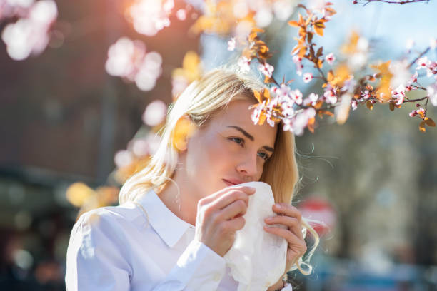Woman sneezing in the blossoming garden Woman sneezing into a tissue hayfever stock pictures, royalty-free photos & images