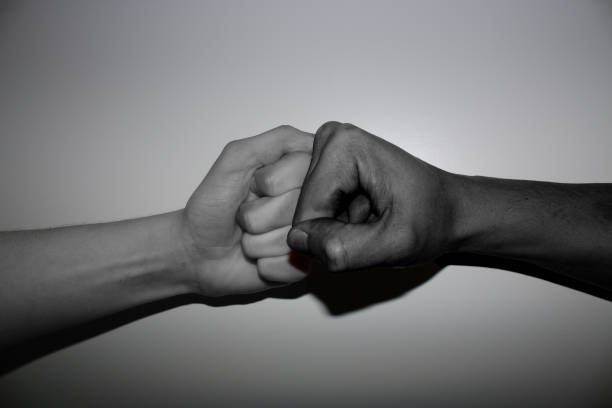 istock Hand gestures - Fist bump of two differenend - multi coloured hands in black and white 1136448353