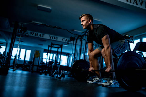 homem novo na ginástica executando um treinamento deadlift-posição inicial - crouching barbell weightlifting weight training - fotografias e filmes do acervo