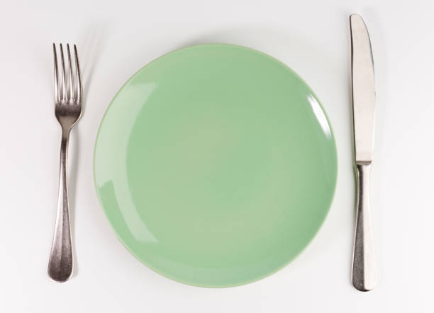 istock empty green plate with fork and knife isolated on white background, top view 1136449465