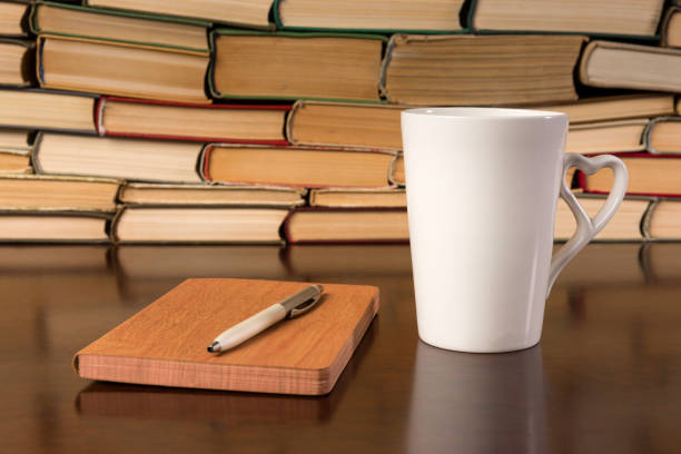 istock Old books on wooden table with tea and open notebook 1136449546