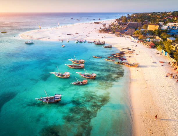 widok z lotu ptaka na łodzie rybackie na tropikalnym wybrzeżu morza z piaszczystą plażą o zachodzie słońca. letnie wakacje na oceanie indyjskim, zanzibarze, afryka. krajobraz z łodzią, budynkami, przezroczystą niebieską wodą. widok z góry - zanzibar zdjęcia i obrazy z banku zdjęć