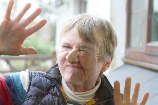 istock senior woman with face pressed against glass 1136458351