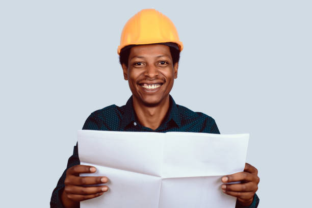 istock Afro american architect in hard hat with blueprint. 1136460785