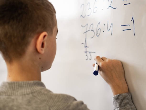 istock Rear view schoolboy writing on whiteboard 1136462350