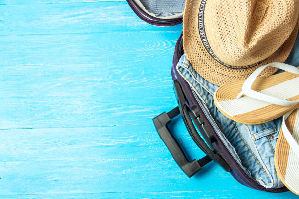 istock Open suitcase with travel accessories on blue wooden table with copyspace. 1136466162
