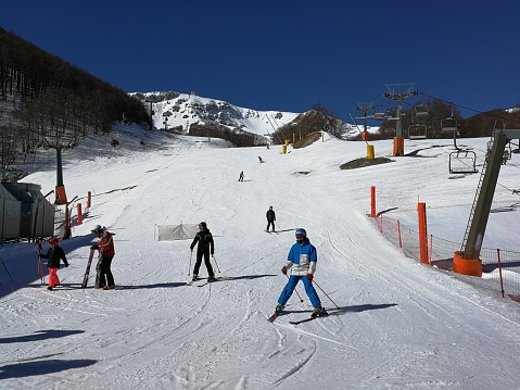 Roccaraso, L'Aquila, Abruzzo, Italy - March 15, 2019: Skiers at the end of the ski slope of the Macchione ski resort, on the Aremogna