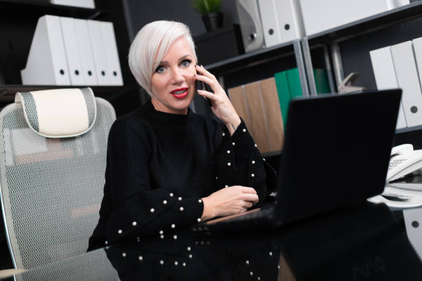 istock Beautiful woman talking on phone sitting at table in office 1136476719