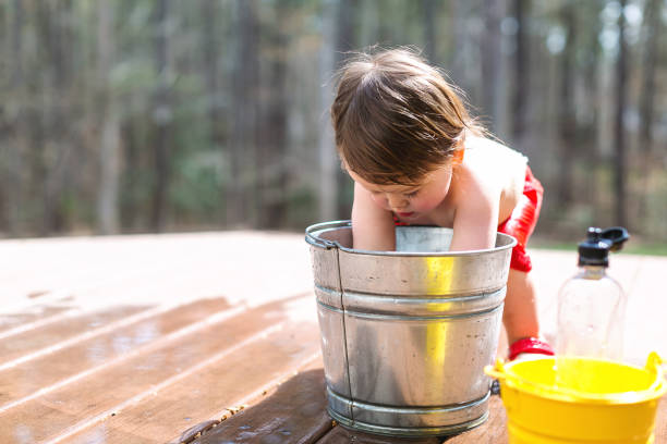 Happy toddler boy playing outside with buckets of water