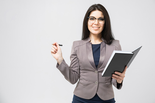 confident businesswoman with a diary in her hands stands against a white wall. business and enterprise concept