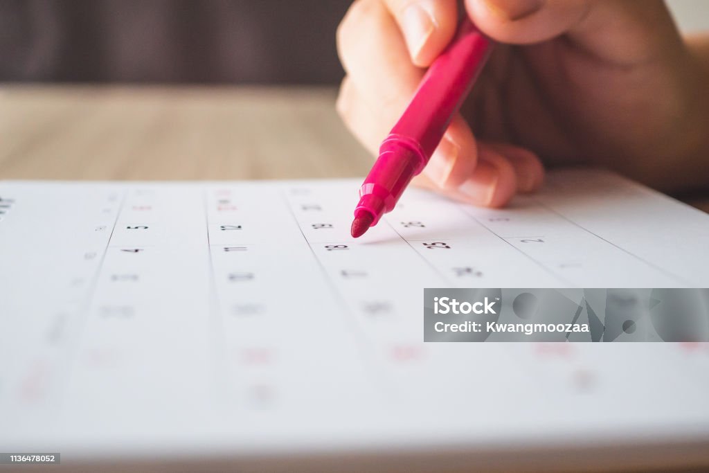 Hand with pen writing on calendar page closeup Calendar Stock Photo