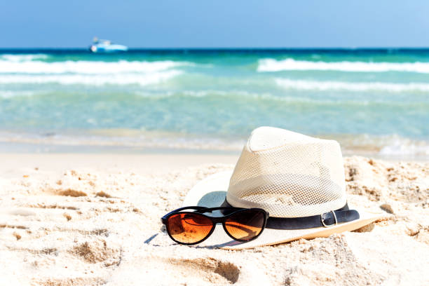 Close up straw hat and sunglasses  on tropical beach and white sandy background. Summer vacation concept. traveling and relax.